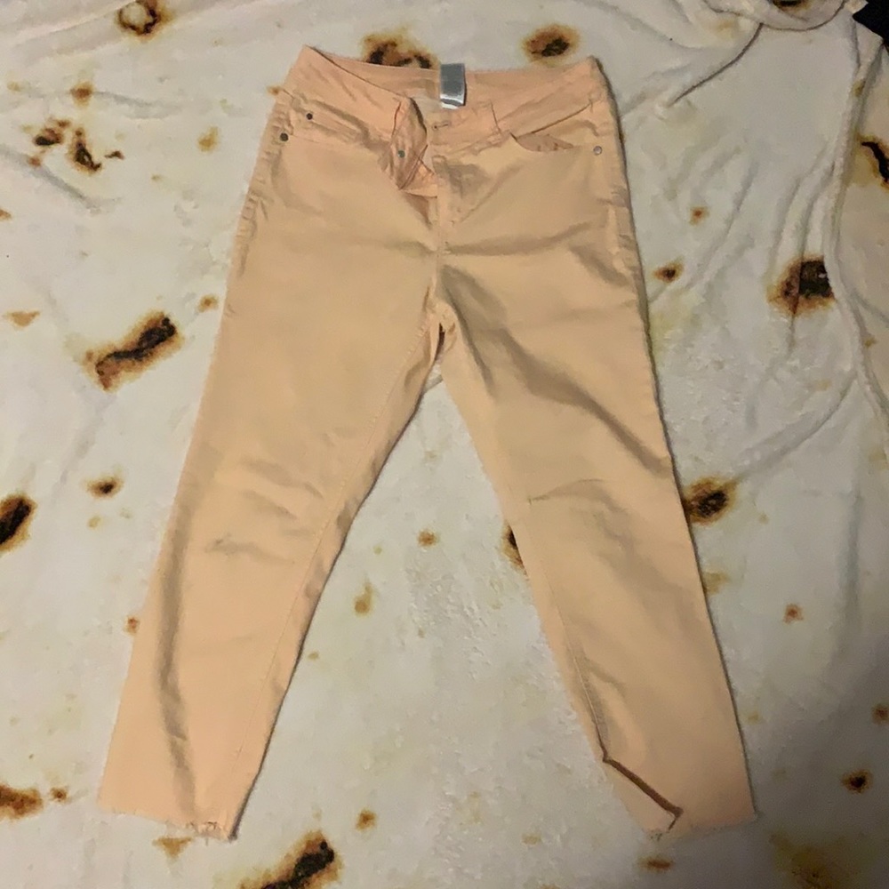 Peach jeans with ripped on bottom pants leg